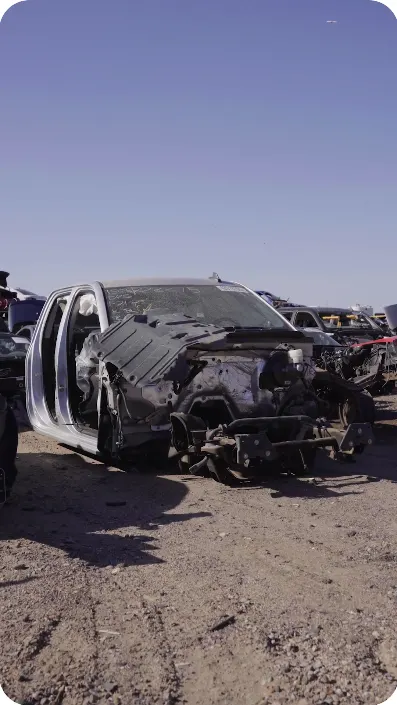 Wrecked silver truck at an auto salvage yard
